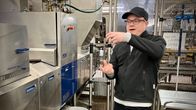 Silmälasipainen henkilö seisoo kananmunien pakkaskoneen edessä.