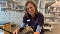 En kvinna i veterinärkläder håller i en hund