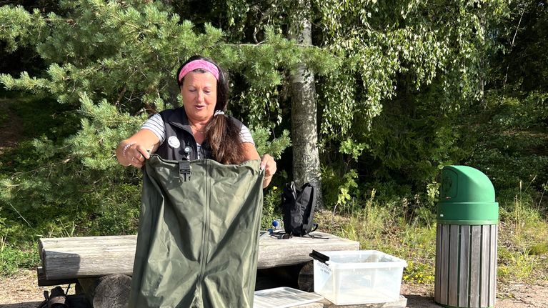 En kvinna sätter på sig vadarbyxor.