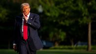 Donald Trump kävelee Valkoisen talon pihamaalla. Hänellä on tumma puku ja kirkkaanpunainen iso kravatti.