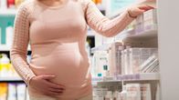 Gravid kvinna tittar på produkter i ett apotek.