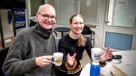 En man och en kvinna dricker termoskaffe i en radiostudio.