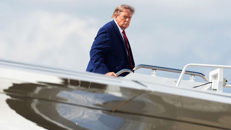 Donald Trump kävelee lentokoneen portaissa taustalla vaalea taivas.