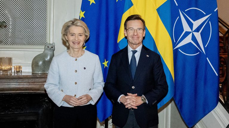 Ursula von der Leyen ja Ulf Kristersson poseeraavat vierekkäin, taustalla Ruotsin, EU:n ja Naton liput.