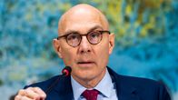 Volker Turk sinisessa puvussa mikrofonin edessä, käsi mikrofonin varressa.