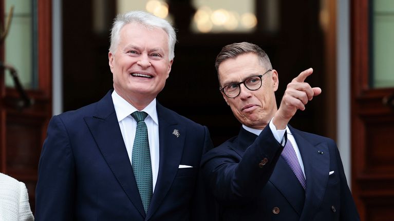 Gitanas Nausėda ja Alexander Stubb seisovat vierekkäin. Stubb osoittaa etusormellaan yläviistoon. Nausėda hymyilee.