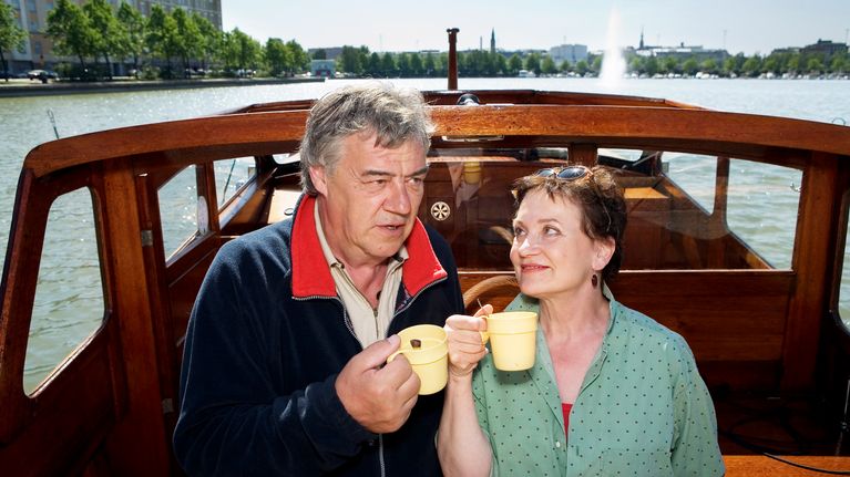 Kotikadun Mauri ja Monika kippistävät kahvikupeilla veneessä.