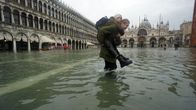 En man bär en kvinna över en översvämmad Piazza San Marco i Venedig.