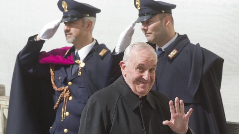 Kardinaali Jorge Mario Bergoglio hymyilee ja vilkuttaa.