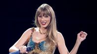 Taylor Swift på scen med mikrofon i handen.