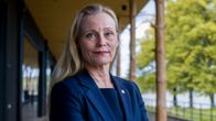 Kvinna med långt blont hår, utomhus i blå kavaj med armarna i kors.