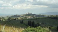 Kumpuileva toskanalaismaisema, taustan kukkulalla näkyy San Gimignanon pikkukaupungin tornirakennukset.