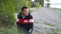 Mies seisoo syksyisessä säässä kalliolla.