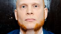 Siniseen pukuun pukeutunut henkilö istuu lattialla.