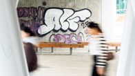 Ihmiset kävelevät graffitien ohi.