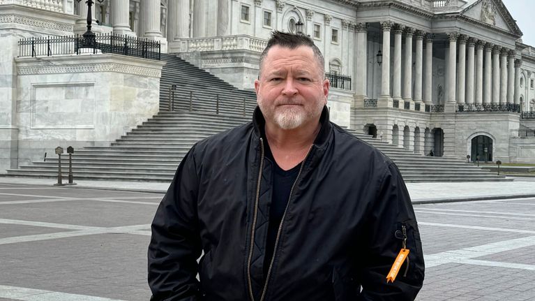 Pentagonin entinen tiedusteluvirkamies Luis Elizondo katsoo kameraan Capitol-rakennuksen edessä.