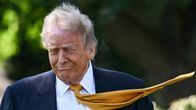 Donald Trumpin keltainen kravatti lentää tuulessa vaakasuoraan. 