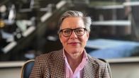 Lena Andersson ler mot kameran sitter i en stol.