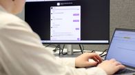 Vaaleapaitainen henkilö naputtelee tietokonetta j taustalla näkyy näytöllä oleva keskustelu teköälybotin kanssa.