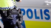 Poliisi seisoo pistooli vyöllään poliisiauton vieressä.