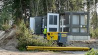 Kaksi ihmistä huomioliiveissä ja kypärissä sähköakkuvaraston vieressä. Kuvassa näkyy sähköakkuvarasto metsän reunassa.