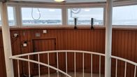 Kokemäne vanhan vesitornin sisätila, paneloidun seinän yläreunassa ikkunarivistö, josta näkyy talvinen maisema