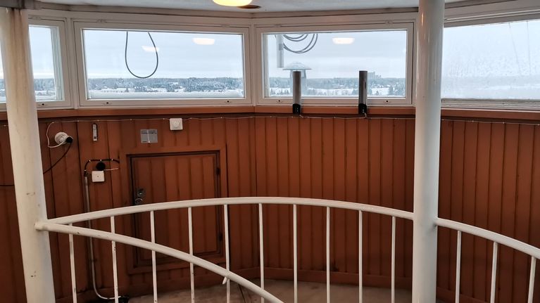 Kokemäne vanhan vesitornin sisätila, paneloidun seinän yläreunassa ikkunarivistö, josta näkyy talvinen maisema