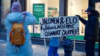 Mielenosoittajia ja vanerinen kyltti kadulla.