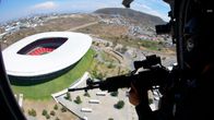 Stadion i Guadalajara sedd från en helikopter. I förgrunden syns en silhuett av ett gevär.