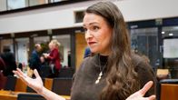 Anna-Kaisa Ikonen hymyilee kokoussalissa ja levittää käsiään.