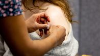 En kvinna vaccineras och får ett plåster på armen.