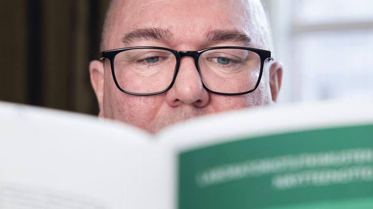 Mies lukee kirjaa, hänestä näkyy vain silmät.