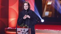 Jessica Grabowsky uppe på scenen vid mikrofonen med sin guldbagge framför sig på podiet.
