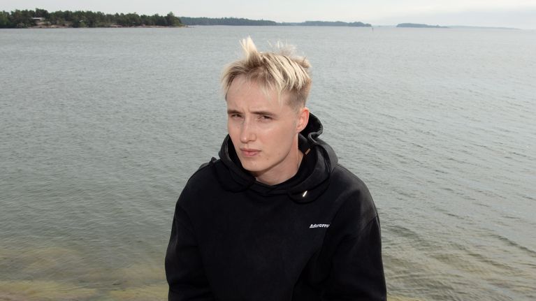 Isac Elliot istuu rantakiveyksellä.