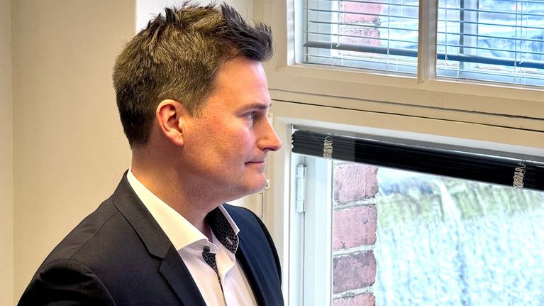 Mikko Koskela istumassa työhuoneessaan. Taustalla ikkunassa näkyy Tammerkoski.