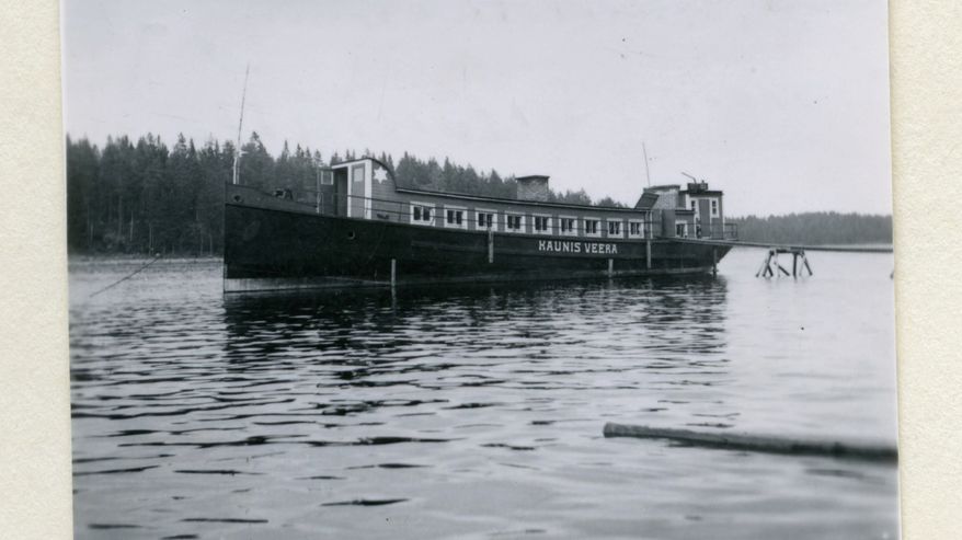 Mustavalkoisessa kuvassa asuntoproomu Kaunis Veera vesillä.