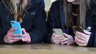 Two young women holding smartphones. 