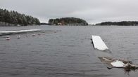 Pielisen ranta, kylmän oloinen järvi. Laituri osittain veden alla, lunta laiturin päällä. Tyhjiä venepaikkoja. 