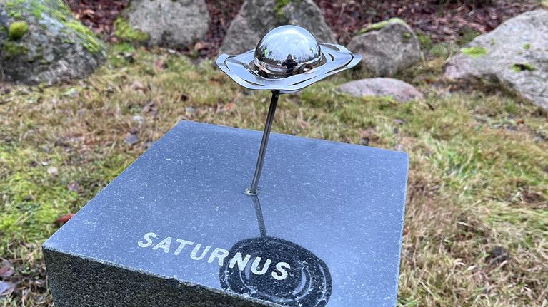 Kuvassa teos, joka kuvaa Saturnusta. Saturnuksen kehää on väännetty mutkalle.