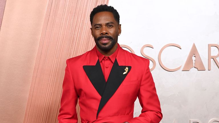 Colman Domingo kirkkaan punaisessa paidassa ja puvun takissa ja mustissa housuissa.