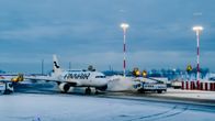 Finnairin lentokoneen siipiä huolletaan talvisessa maisemassa Helsinki-Vantaalla muiden ajoneuvojen avustuksella.