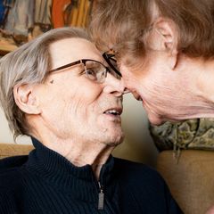 Two elderly people touching noses.