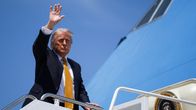 Donald Trump vilkuttaa lentokoneen portailta. 