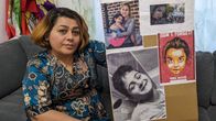 Parvin Shokri käsissään taulu, johon on kerätty Iranissa kuolleiden lasten kuvia.