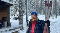 Hanna-Mari Sinilehto seisoo tunturisukset kainalossaan lumisessa metsässä ja katsoo kameraan.