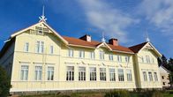 Keltainen, punakattoinen jugendrakennus seisoo remontoituna kesämaisemassa.