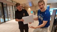 Antti-Jussi Sipilä ojentaa Lauri Markkaselle PlayStation 5 -pelikonsolin.