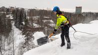 Kattotutkan työntekijä lappaa lunta pois katolta.