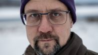Talvinen maisema taustalla, henkilö pukeutunut lämpimästi pipoon ja talvitakkiin.