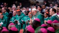 Påve Franciskus stöder sig på sin herdestav som slutar i ett krucifix. Han är klädd i en grön korkåpa och är omgiven av kardinaler och präster i gröna mässhakar.